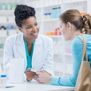 A Pharmacist smiling and assisting a customer at a pharmacy counter