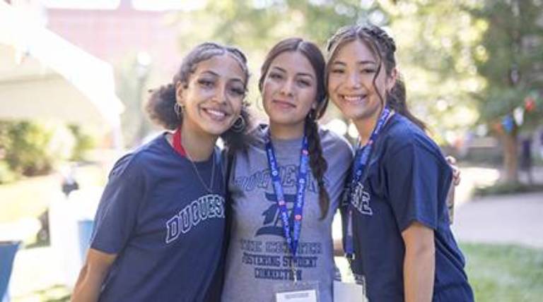 Three 3 girls standing together on a sunny day.