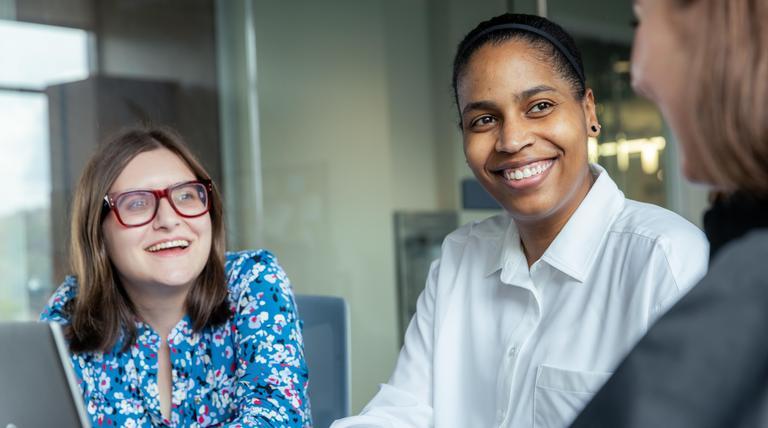 Graduate students talking in front of a laptop in the Palumbo-Donahue School of Business.
