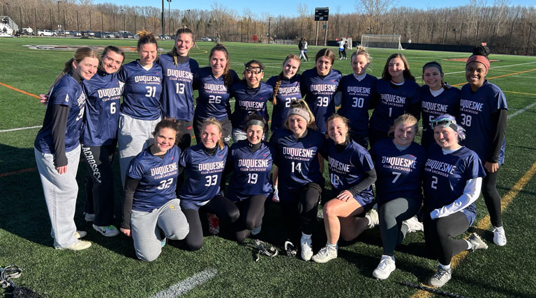 women's lacrosse team posing together on a field