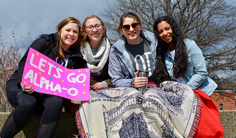 Duquesne Alpha Omicron Pi sorority sisters sitting together outside on campus