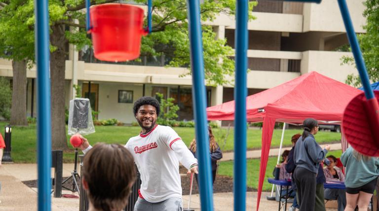 A Duquesne student gets ready to throw a ball at a water bucket at Festival on the Bluff 2026.