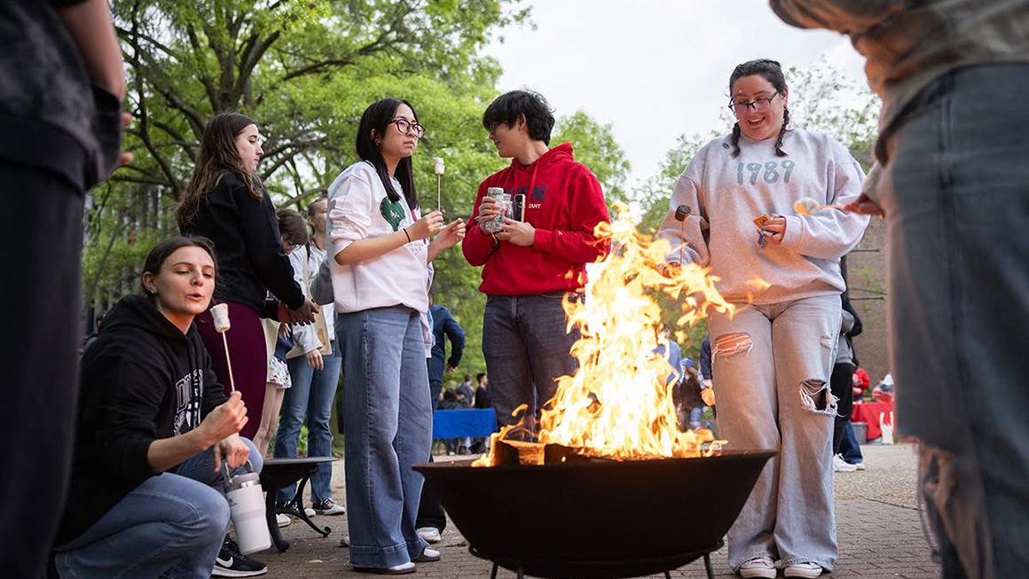 Duquesne students gathering around a fire at Festival on the Bluff