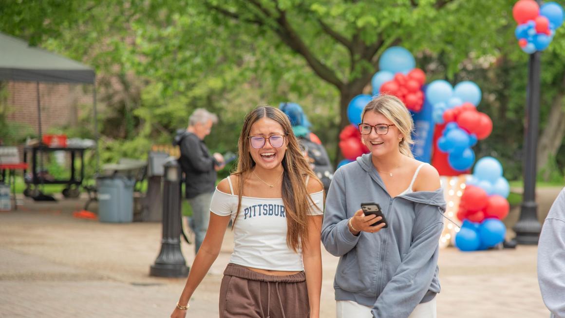 Two Duquesne students walking on A-walk and laughing