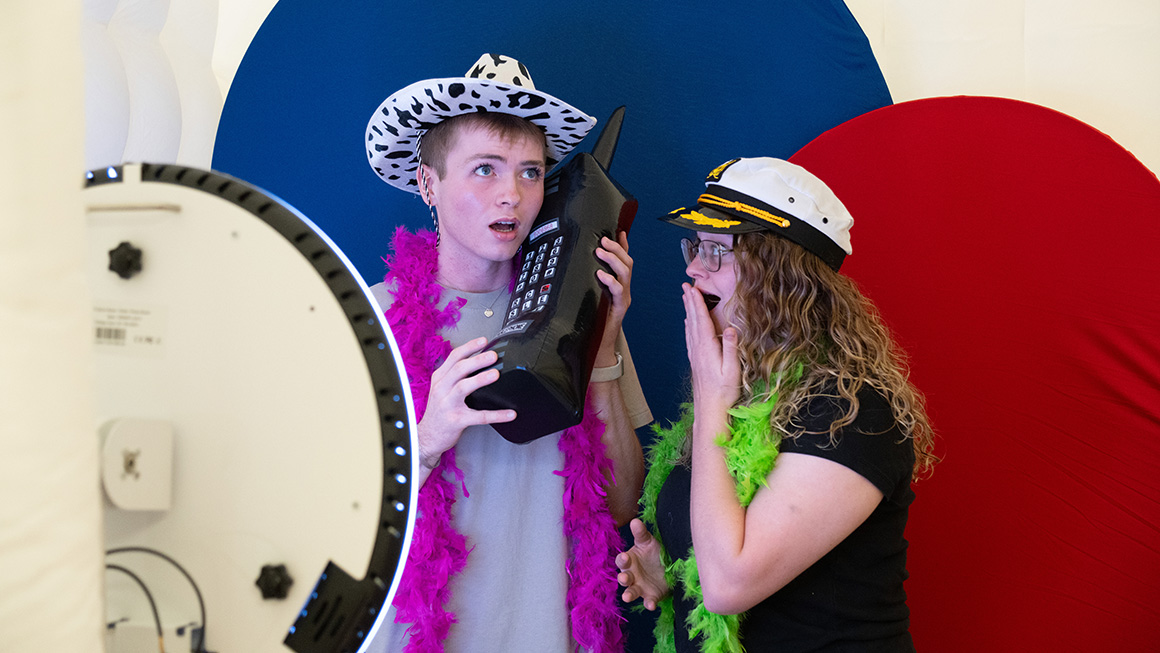Two Duquesne students having fun at a photo booth with an oversized pretend cell phone