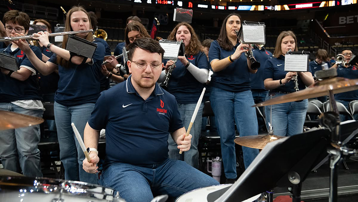 Duquesne student pep band members performing at an NCAA Duquesne Dukes basketball game.