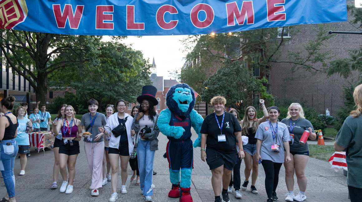 Students walk alongside the Duquesne mascot on A-Walk.