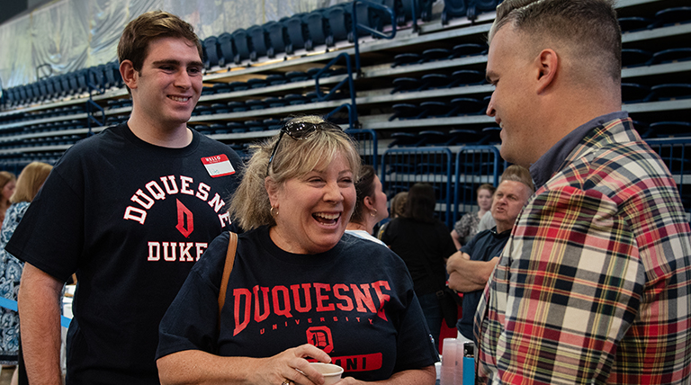 student and parent smile while talking to student life leadership