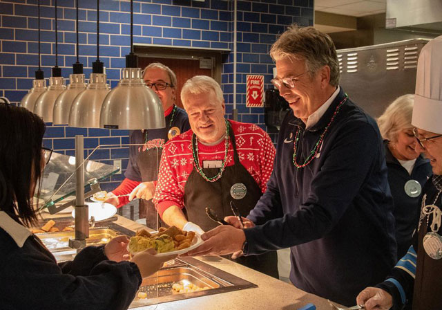 President Gormley, alongside other University staff, serve breakfast to a student during Late-Night Breakfast.