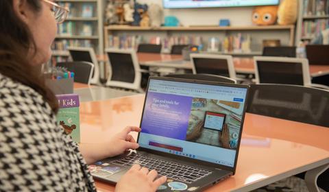 School psychology PhD student sits at a table and looks at YouTube parental controls on her laptop