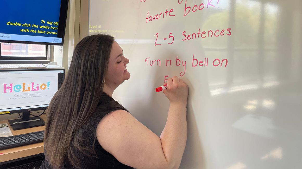 Cassidy Klock writes on a whiteboard in a classroom