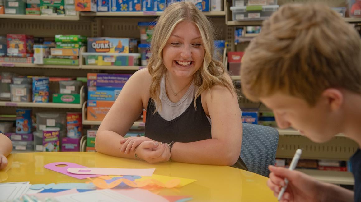 School of Education student Elle Bowers assists a student with his homework at a table