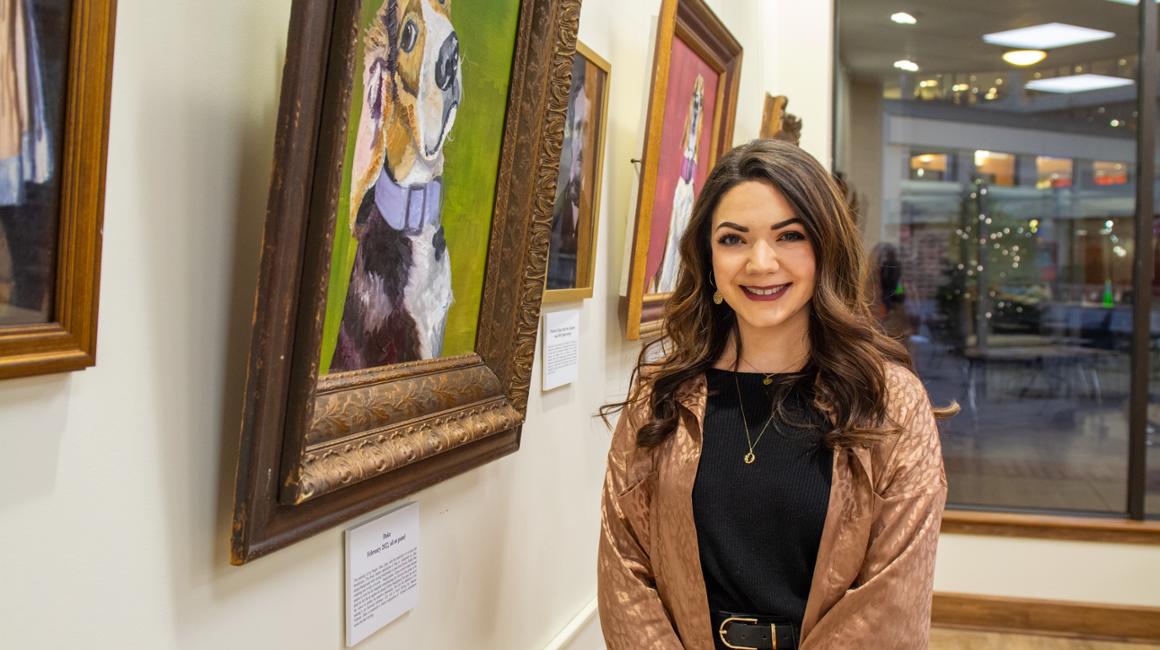 Maralisa Marra stands beside her painting of a beagle in a historical setting.