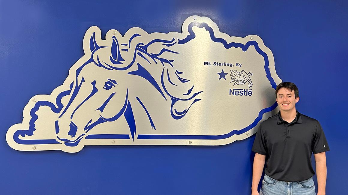 Duquesne School of Business graduate Ronnie Coleman, B'23, standing in front of Nestle's Kentucky-based logo.
