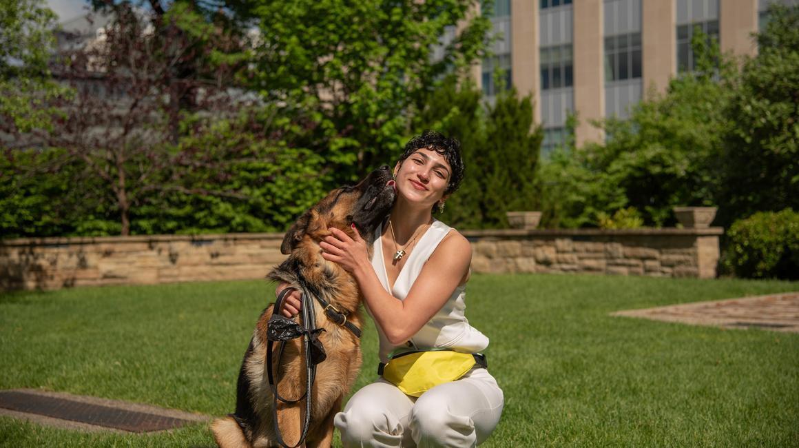 Rosie Franjoine sits in the grass on campus alongside Polo, the German Shepherd she trains