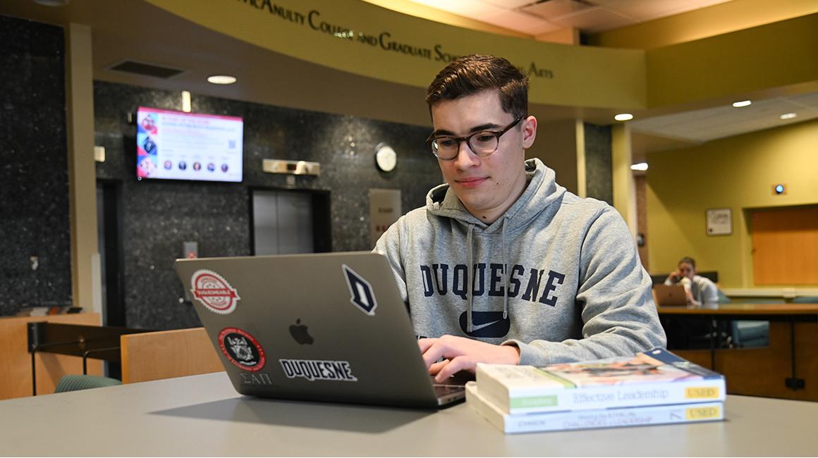Ryan Stoudt studies on his laptop in the lobby of College Hall