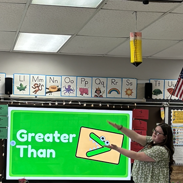 Kendall House demonstrates math concepts in front of a screen in an elementary school classroom.