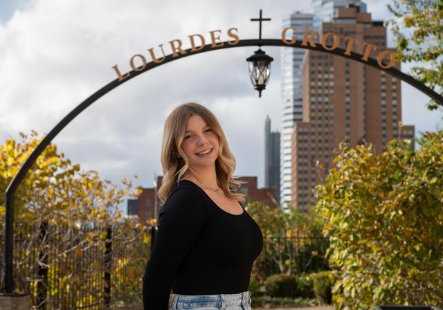 Riley Adams stands in front of the entrance to the Lourdes Grotto on Duquesne's campus
