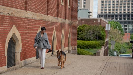 Rosie Franjoine walks Polo, a German Shepherd, on the sidewalk near Old Main on Duquesne's campus.