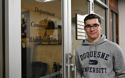 Ryan Stoudt stands outside of the Department of Communications and Rhetorical Studies in College Hall