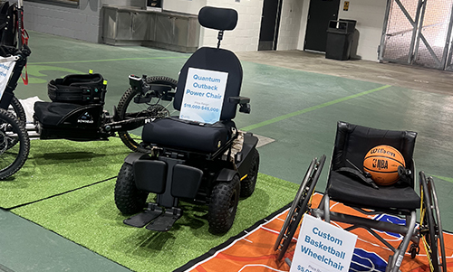 Several different types of wheelchairs sit on display at a fundraising event.