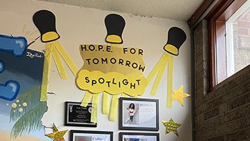 Artwork of a spotlight sits above plaques and photos honoring HOPE for Tomorrow staff.
