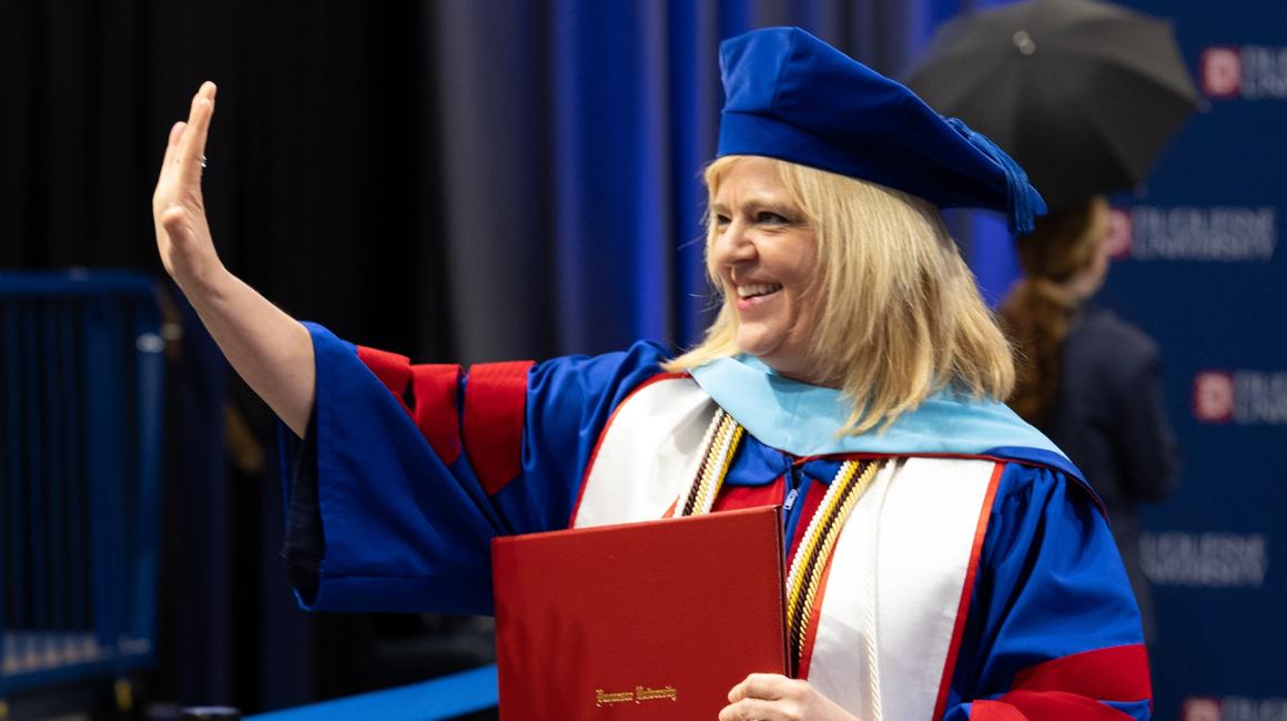 Female graduate waving with diploma