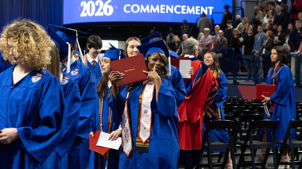 Female graduate pointing to her degree smiling