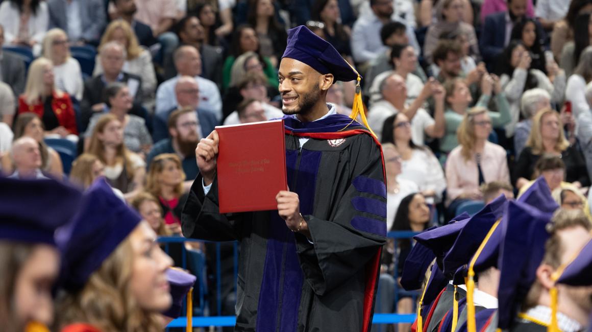 Graduate holding up his Law Diploma