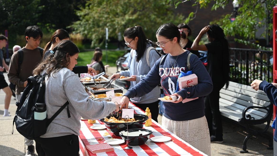 Several students gather outside he library to enjoy carnival-themed snacks.