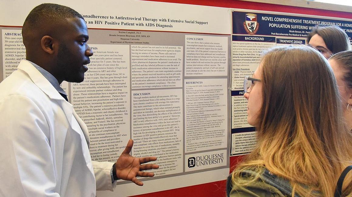 A student presents his poster at the annual Research Symposium