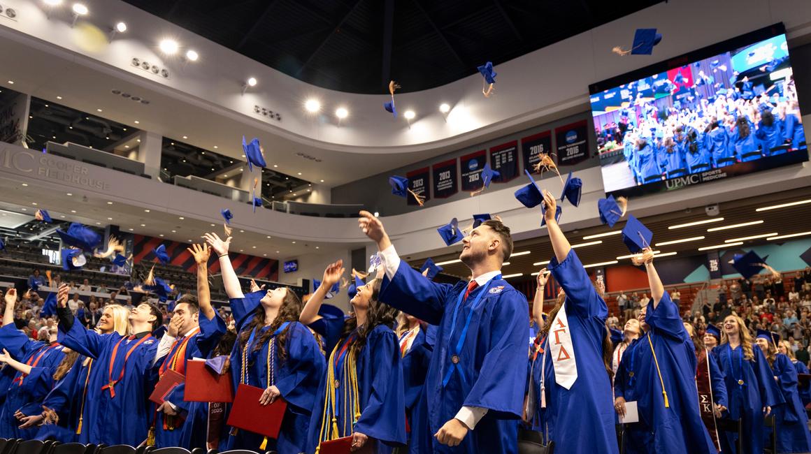Duquesne graduates throw their caps up in the air
