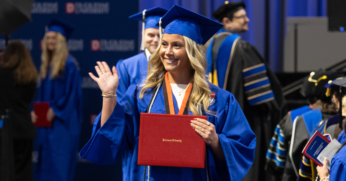 Graduating student with diploma waving