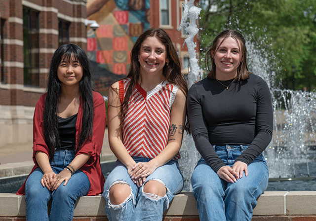 Three female science students sitting in front of fountain