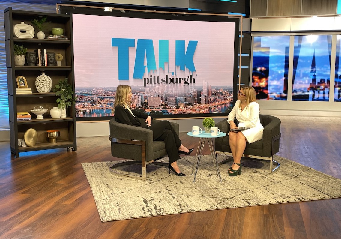 student maggie burke sitting on set of television program with host of the show