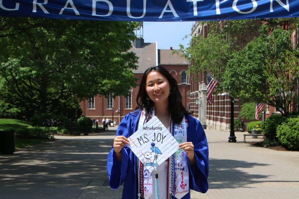 Joy Chen stands on Academic Walk wearing her cap and gown