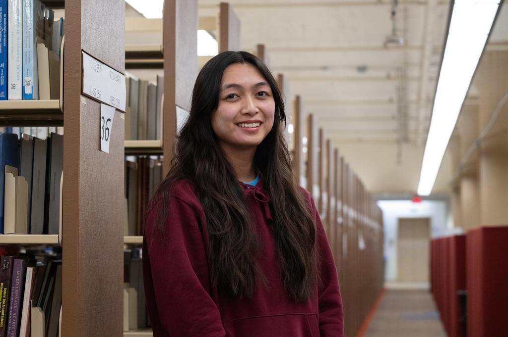 Ranelle leans against a bookshelf in the library