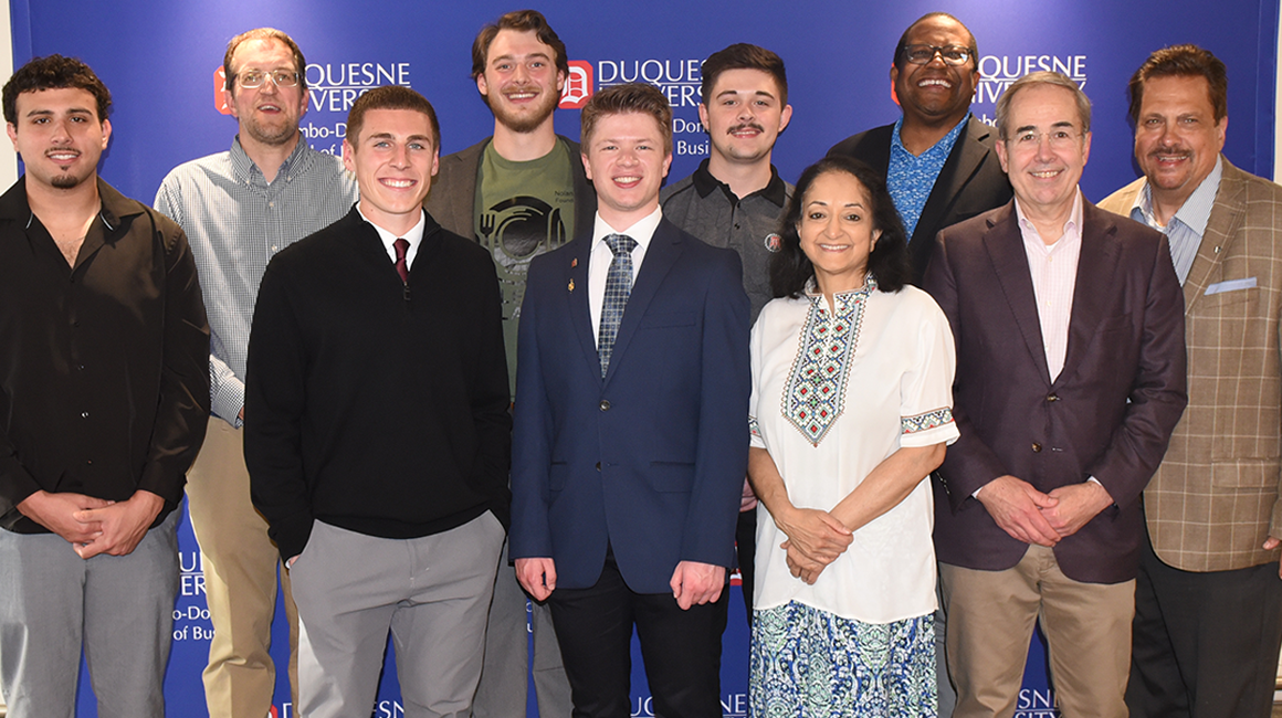 Winners and judges of the '24-'25 DNVC pose for a photo in front of a Duquesne University backdrop