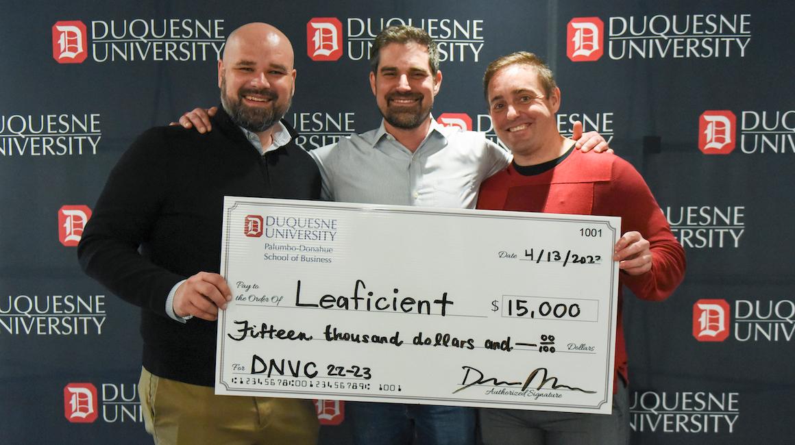 group of students smiling at camera holding up a large check