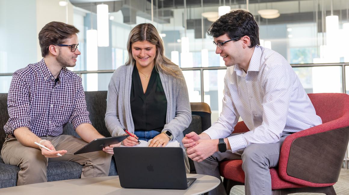 group of business students smiling and computer