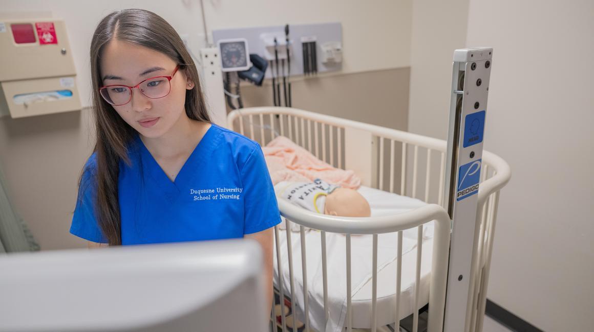 School of Nursing student Abby Stanley takes notes on a med cart in the nursing simulation lab.