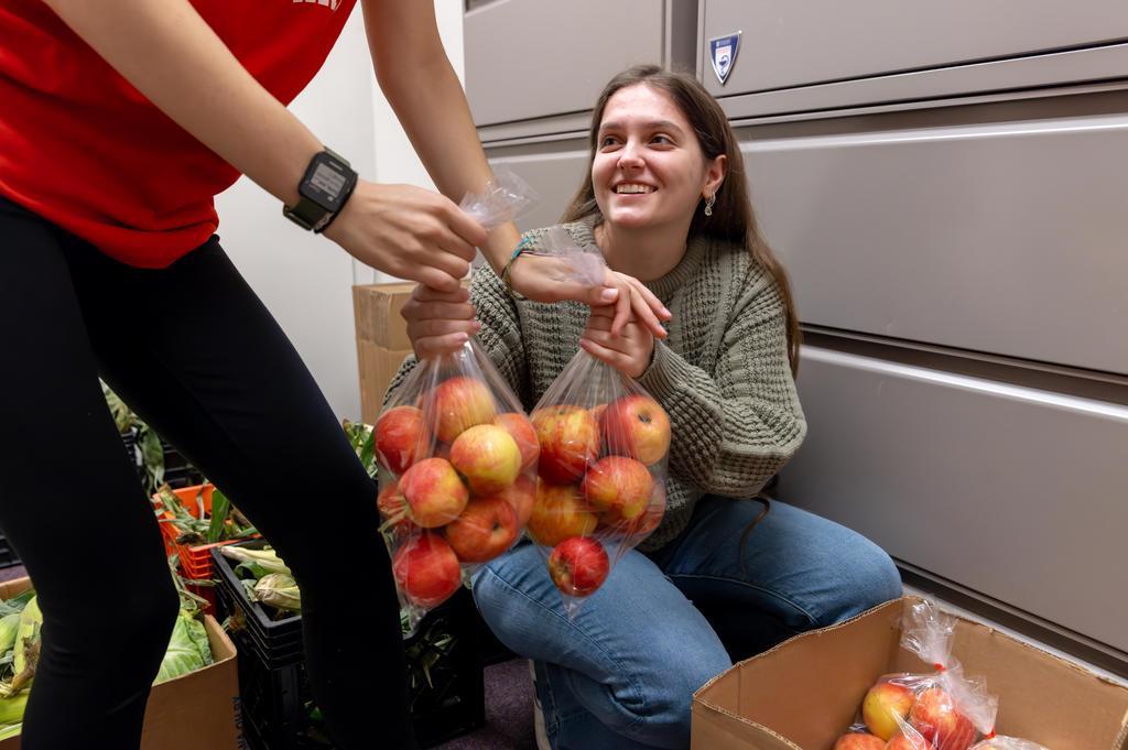 A student worker in the McAnulty Keating Pantry being handed a bag of apples