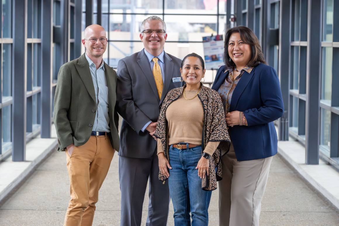 three panelists from the 2025 tech ethics symposium pose with  john slattery for group photo on skywalk