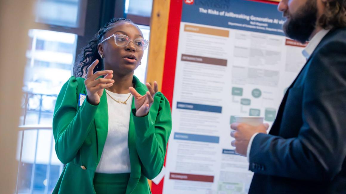 student explains their research poster to an attendee at the 2025 tech ethics symposium