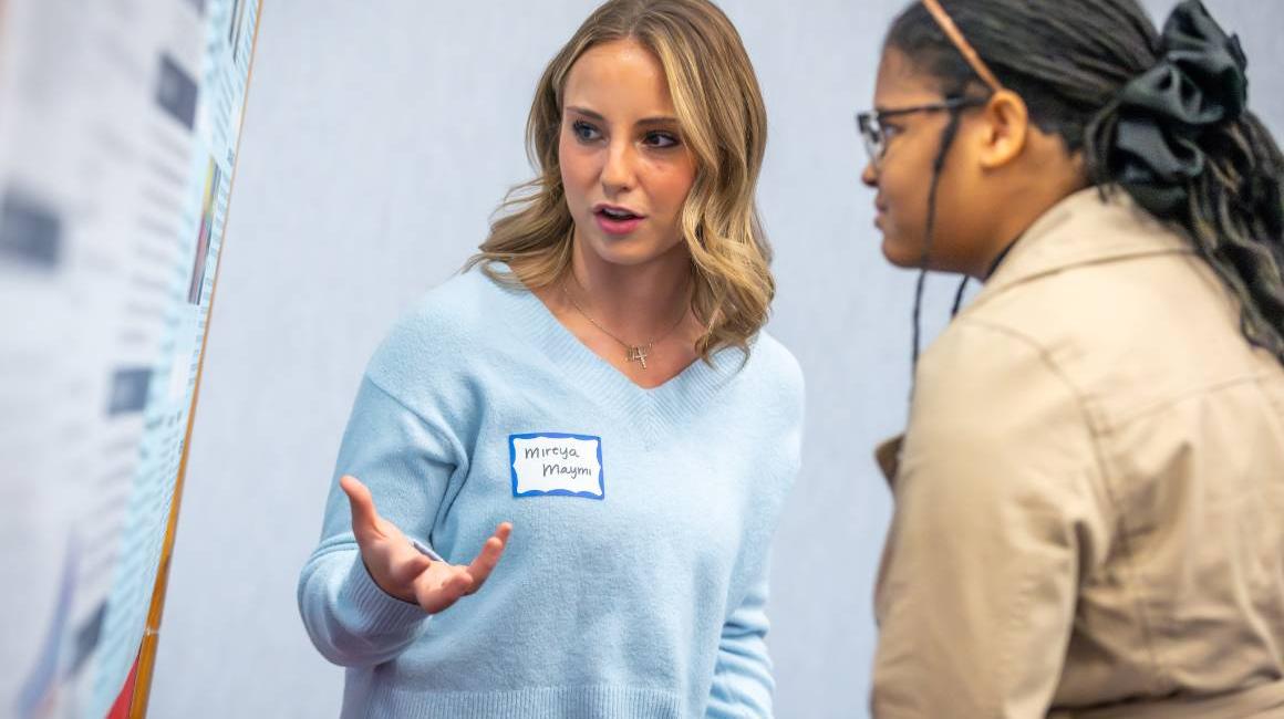 student presenter discusses poster with student attendee at the 2025 tech ethics symposium