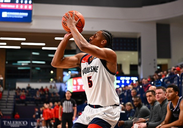 Duquesne University men's basketball player taking a shot with crowd watching