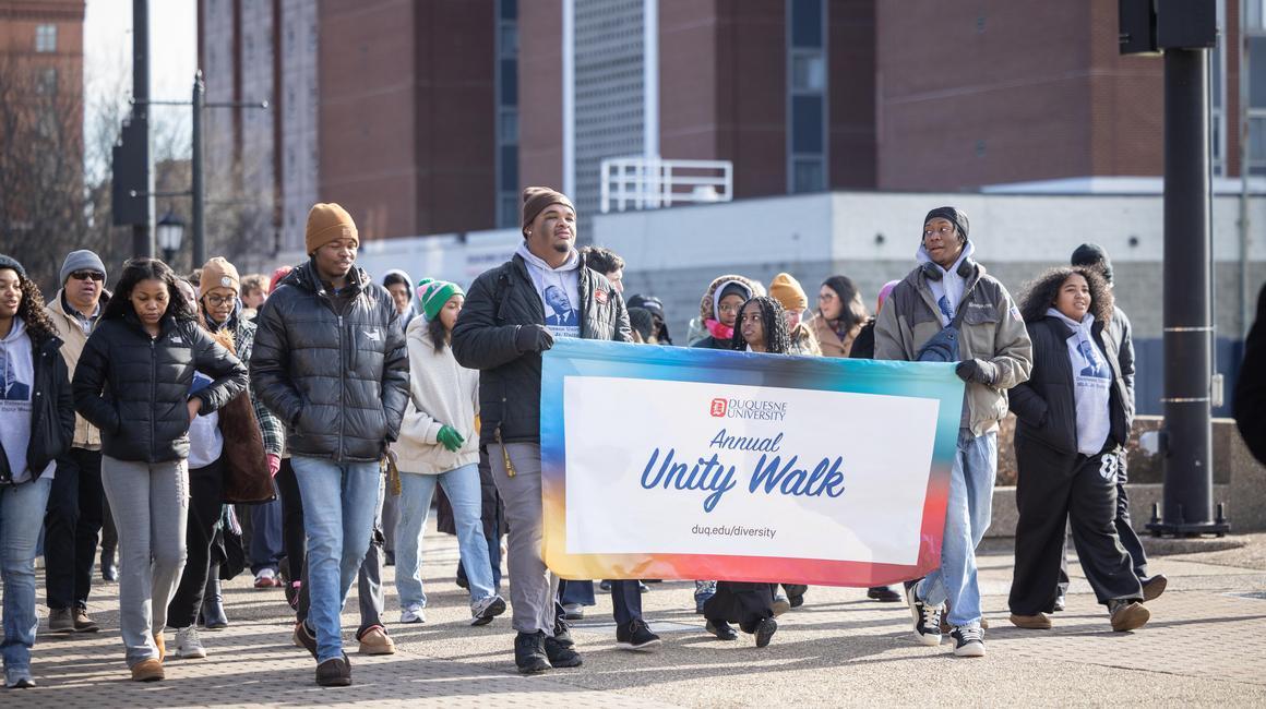 MLK Unity Walk 2026 participants walking up the hill with Duquesne Towers in the background