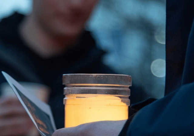Candle with light flickering in a hand.