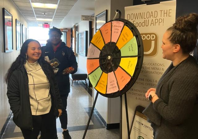 3 people next to a wheel of options.