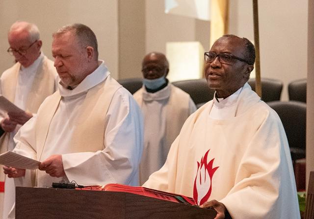 Priests standing at the priest's chair during a mass gathering